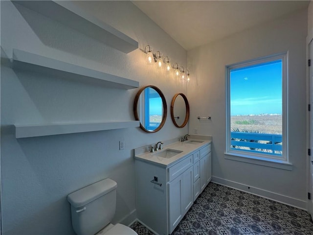 bathroom featuring a sink, baseboards, toilet, and double vanity