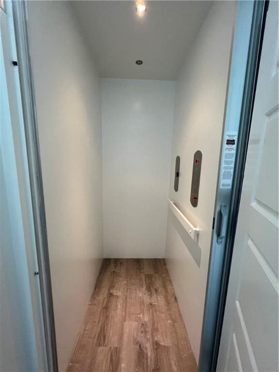 hallway with elevator and wood finished floors