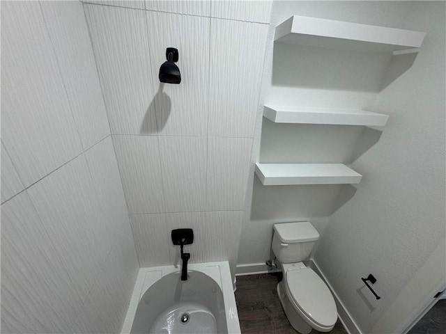 full bath featuring a bath, toilet, baseboards, and wood finished floors