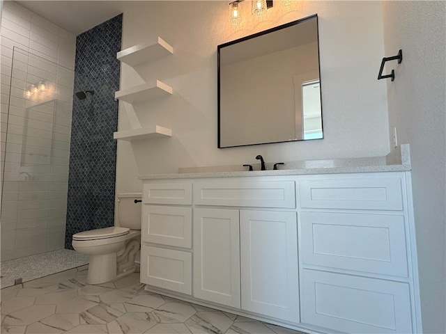 bathroom with vanity, toilet, marble finish floor, and a tile shower