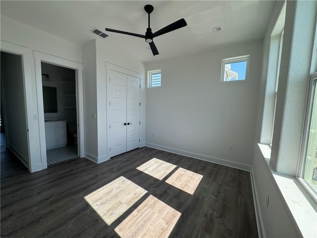 unfurnished bedroom featuring dark wood-style floors, visible vents, and baseboards