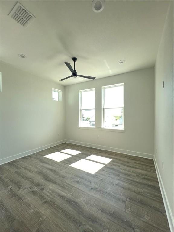 unfurnished room featuring ceiling fan, dark wood-style floors, visible vents, and baseboards