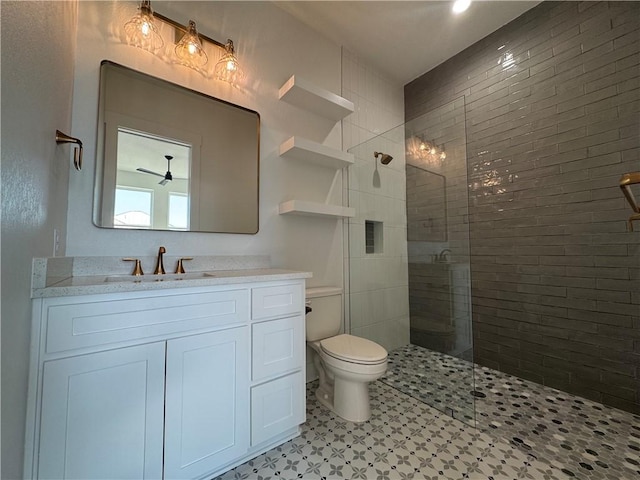 full bathroom with a tile shower, toilet, and vanity