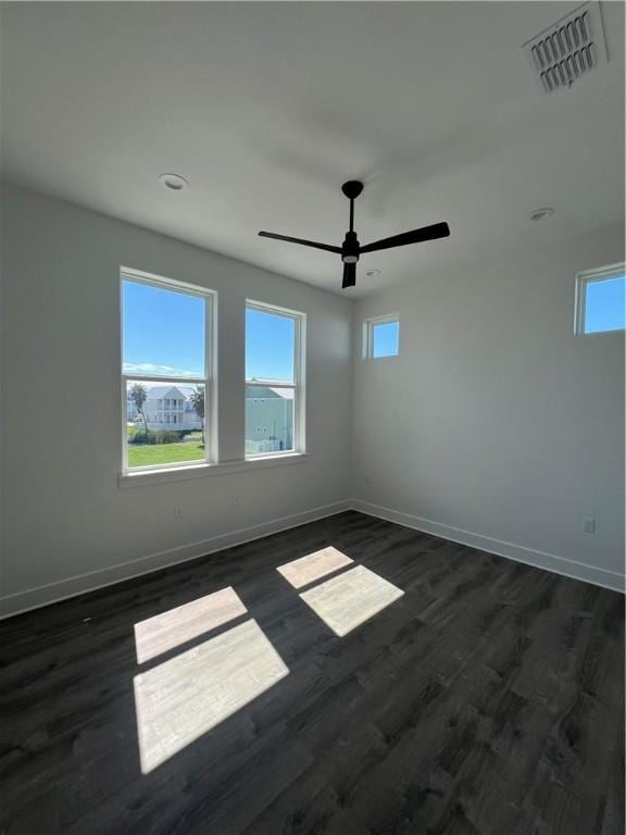 spare room with a wealth of natural light, visible vents, dark wood-type flooring, and baseboards