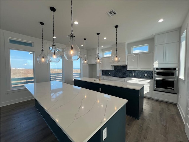 kitchen featuring visible vents, a spacious island, decorative backsplash, dark wood-type flooring, and double oven