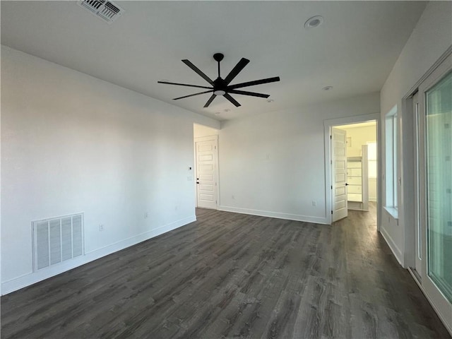 empty room featuring dark wood-style floors, visible vents, and baseboards