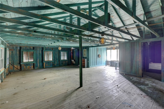 misc room with wood walls, wood-type flooring, and vaulted ceiling