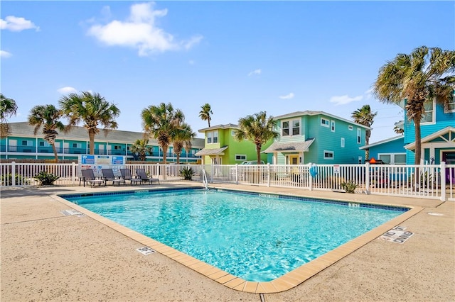 pool with a patio, fence, and a residential view