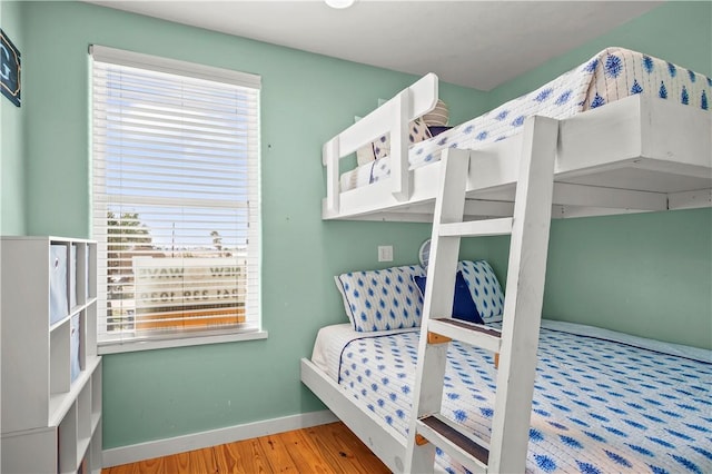 bedroom featuring multiple windows, wood finished floors, and baseboards