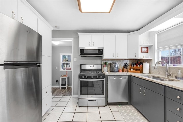 kitchen with sink, appliances with stainless steel finishes, gray cabinetry, white cabinets, and light tile patterned flooring