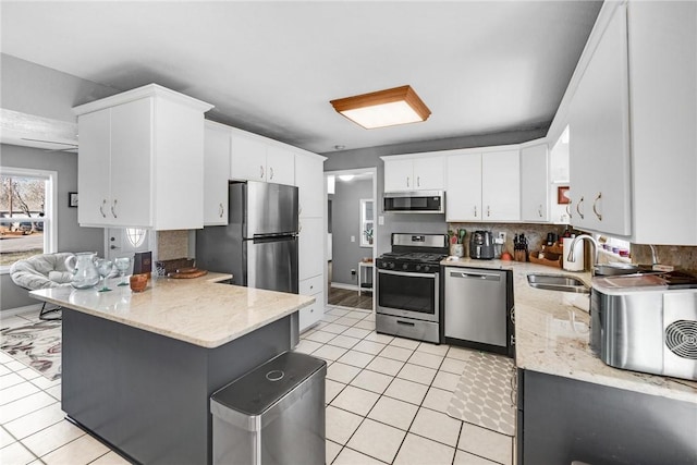 kitchen with light tile patterned flooring, appliances with stainless steel finishes, sink, and white cabinets