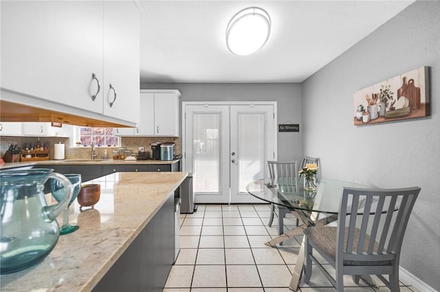 kitchen featuring sink, white cabinetry, light tile patterned floors, light stone countertops, and decorative backsplash