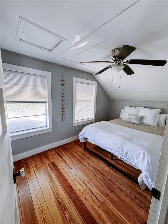 bedroom featuring attic access, baseboards, a ceiling fan, lofted ceiling, and hardwood / wood-style floors