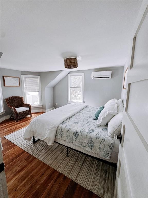 bedroom with an AC wall unit and wood finished floors