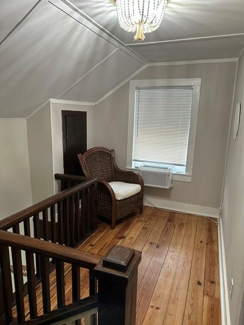 bonus room with wood-type flooring, a chandelier, vaulted ceiling, and baseboards