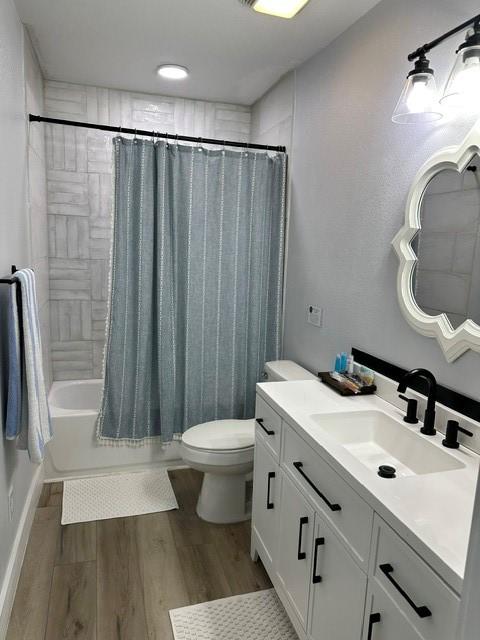 bathroom with shower / tub combo with curtain, vanity, toilet, and wood finished floors