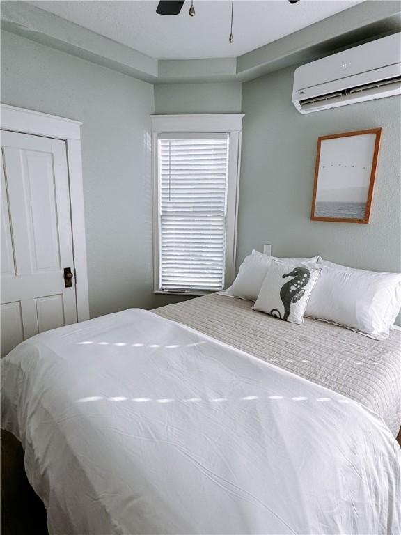 bedroom featuring a ceiling fan and a wall mounted AC