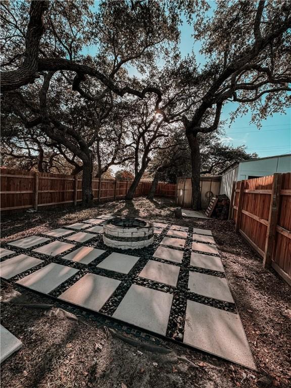 view of yard featuring a fenced backyard, a fire pit, an outbuilding, and a patio