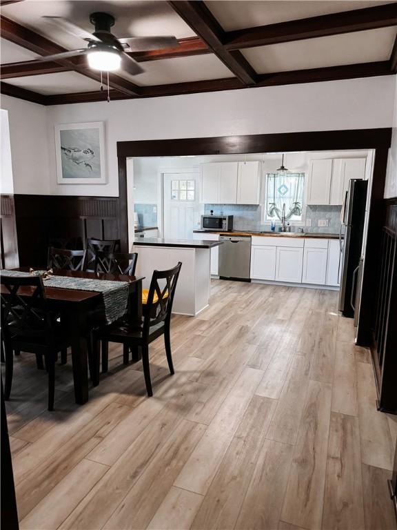 kitchen with tasteful backsplash, light wood-style flooring, appliances with stainless steel finishes, white cabinetry, and beam ceiling