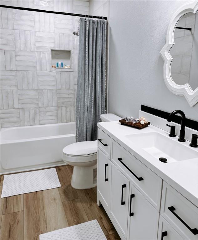 full bathroom with toilet, shower / bath combo, wood finished floors, and vanity