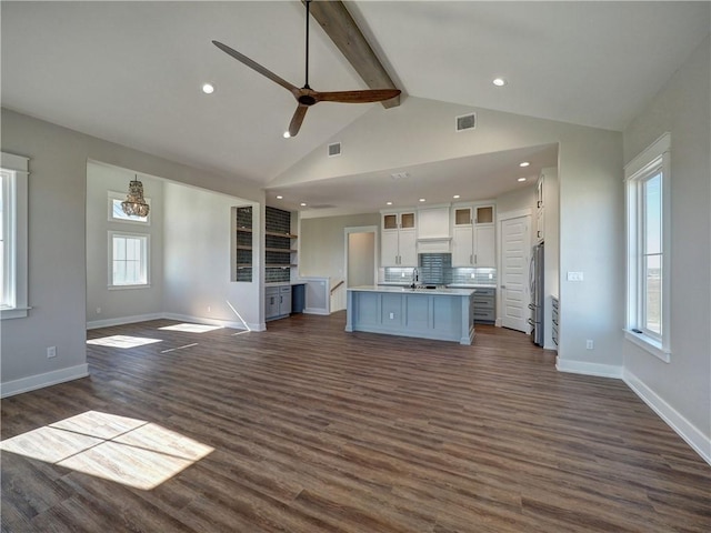 unfurnished living room with beamed ceiling, dark hardwood / wood-style floors, ceiling fan, and sink