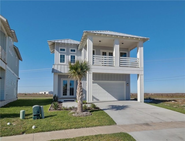 view of front of property featuring a garage, a balcony, a front yard, and french doors