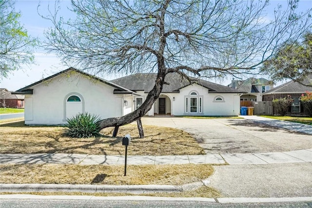 view of front of home with driveway, fence, and stucco siding