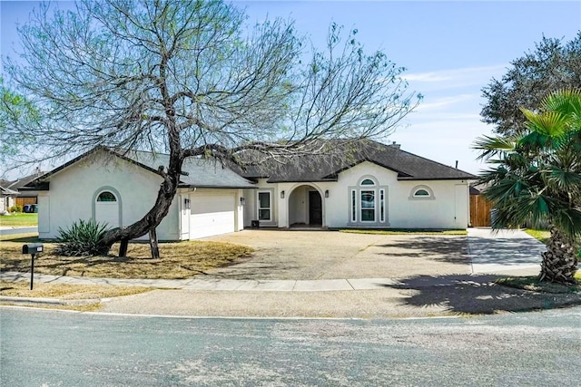 view of front facade with a garage, driveway, and stucco siding