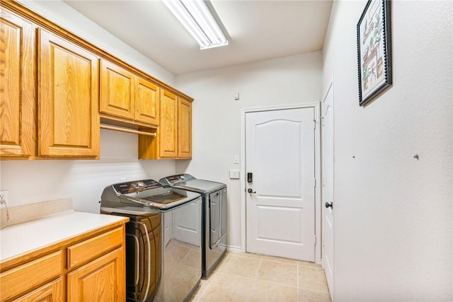 washroom with light tile patterned flooring, washing machine and dryer, and cabinet space