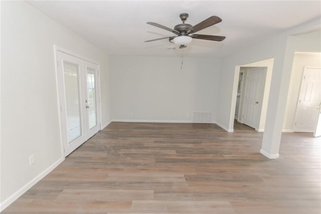 unfurnished room with ceiling fan, visible vents, baseboards, and wood finished floors