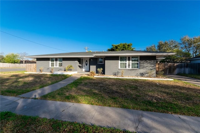 ranch-style home with a front yard and fence