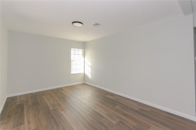 unfurnished room with visible vents, baseboards, and wood finished floors