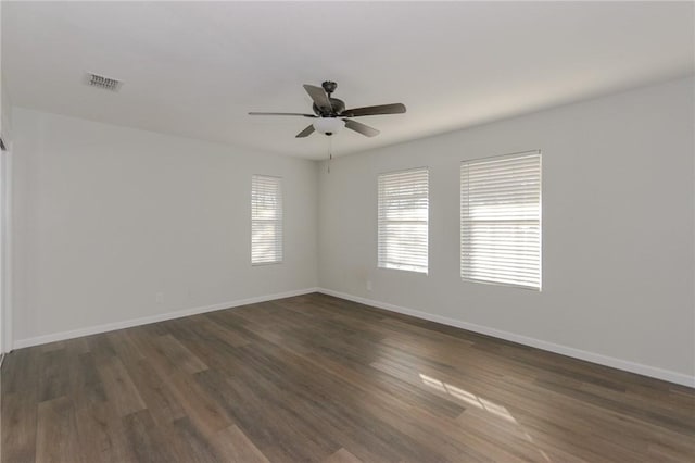 unfurnished room with visible vents, baseboards, and dark wood-style flooring