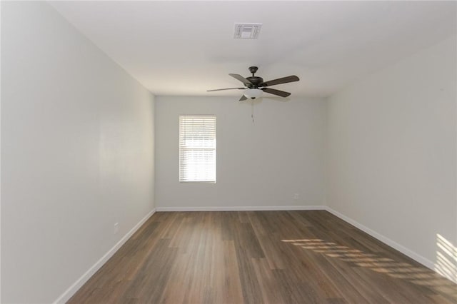 empty room featuring dark wood-style floors, visible vents, ceiling fan, and baseboards