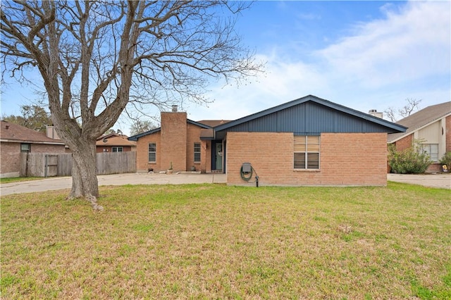 rear view of property featuring brick siding, fence, a lawn, a chimney, and a patio