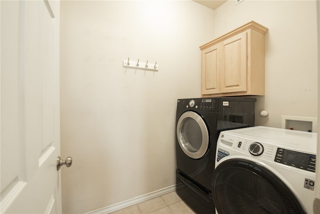 washroom with cabinets, washing machine and dryer, and light tile patterned floors