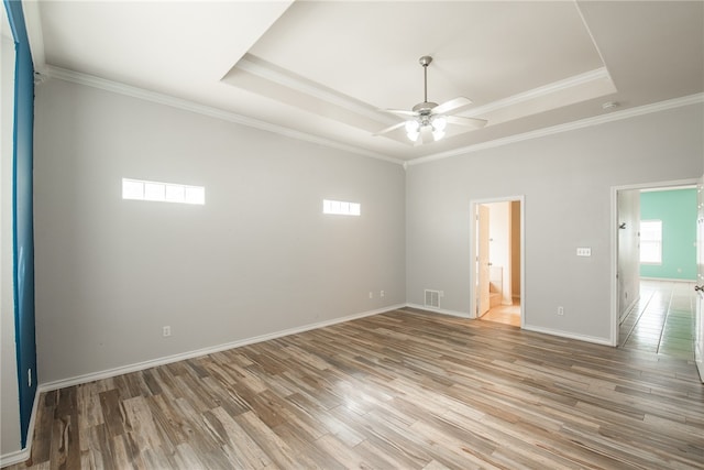 spare room with hardwood / wood-style flooring, ceiling fan, a raised ceiling, and ornamental molding