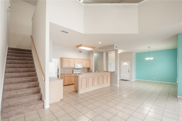 kitchen featuring white appliances, light brown cabinetry, a towering ceiling, and light tile patterned floors