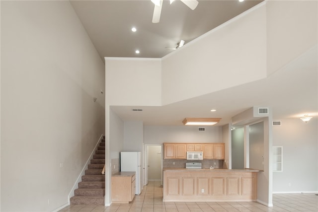 kitchen with tasteful backsplash, light brown cabinetry, a high ceiling, white appliances, and ceiling fan