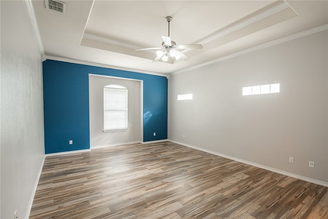 empty room with hardwood / wood-style floors, a raised ceiling, ceiling fan, and crown molding