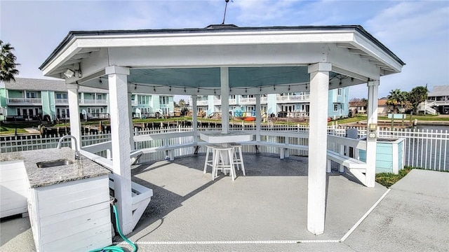 view of patio with a water view, sink, and a gazebo