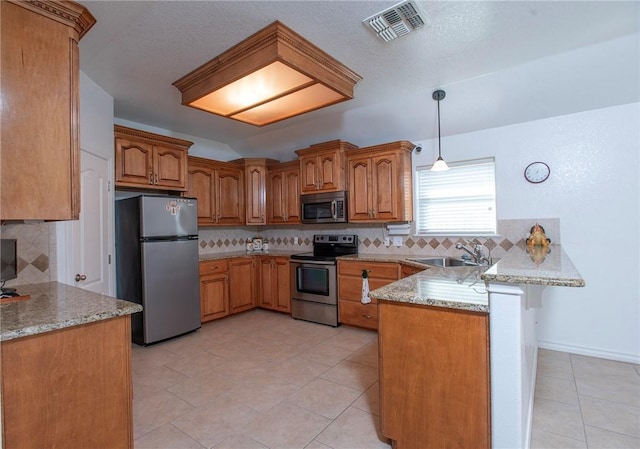 kitchen featuring visible vents, a peninsula, a sink, stainless steel appliances, and brown cabinets