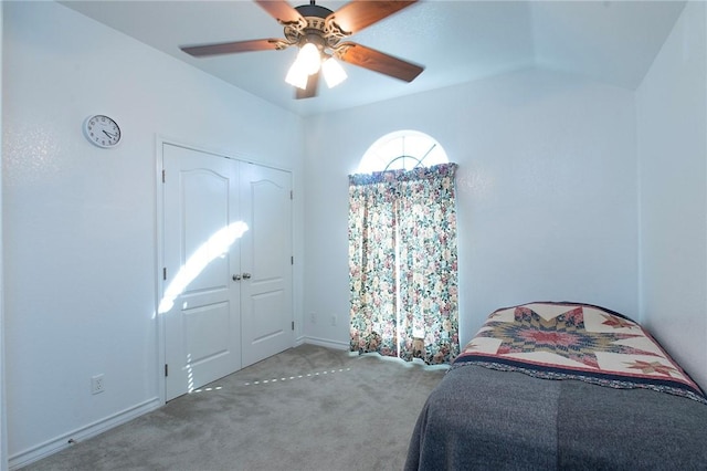 bedroom with a closet, ceiling fan, carpet flooring, and vaulted ceiling