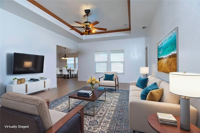 living room with visible vents, a raised ceiling, baseboards, and a ceiling fan