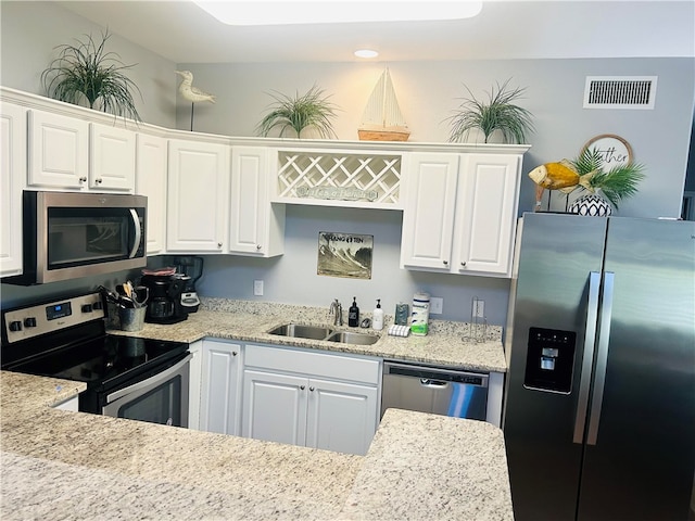 kitchen featuring stainless steel appliances, light stone countertops, white cabinets, and sink