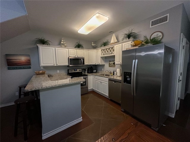 kitchen with white cabinets, kitchen peninsula, sink, a breakfast bar, and appliances with stainless steel finishes