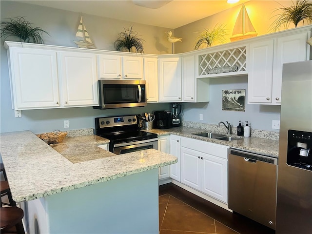 kitchen with dark tile patterned floors, white cabinetry, appliances with stainless steel finishes, and sink