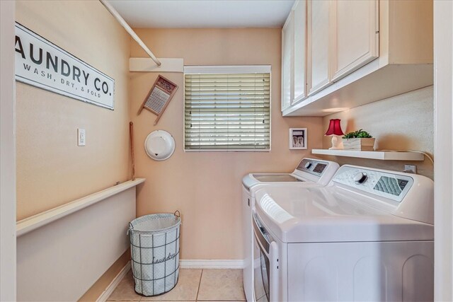 clothes washing area with cabinets, washer and dryer, and light tile patterned floors