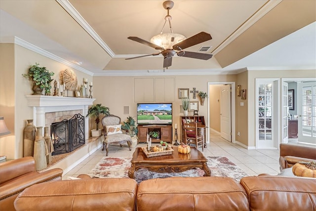 tiled living room featuring ceiling fan, a tile fireplace, a raised ceiling, and ornamental molding