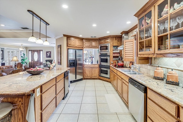 kitchen featuring pendant lighting, appliances with stainless steel finishes, sink, and light stone countertops